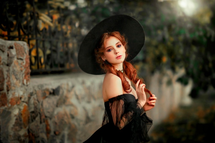Redhead woman in black dress and hat outdoors