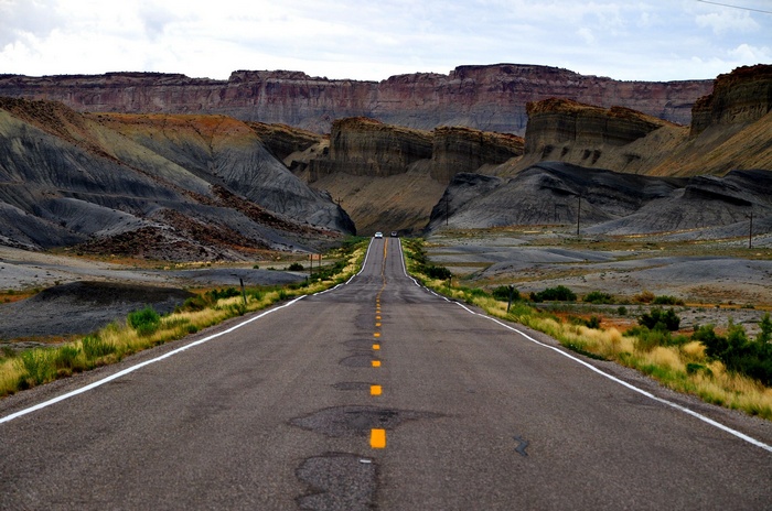 Asphalt road through a desert landscape with mesas