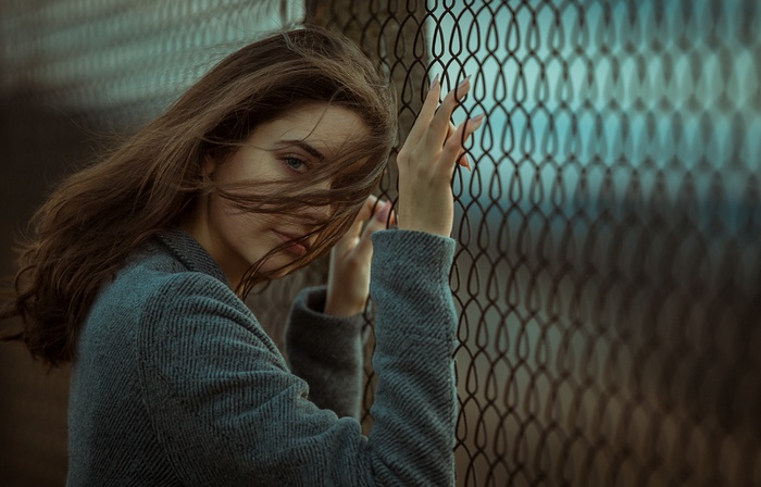 Woman with hair in face leaning on fence