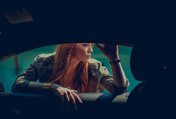 Woman with red hair leaning out of a car window