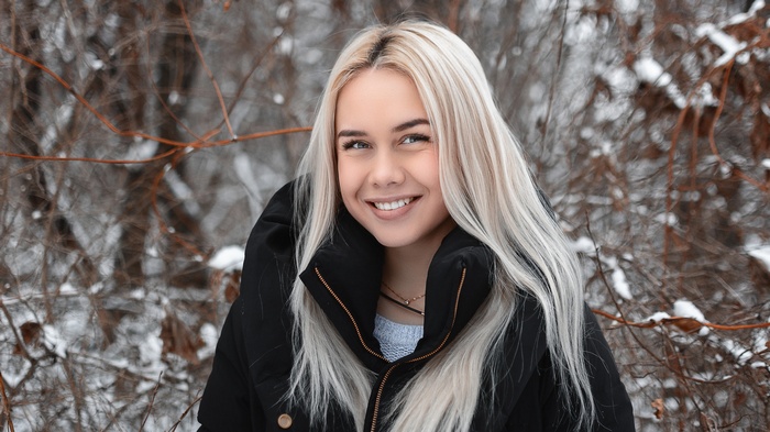 Woman with blonde hair wearing a black jacket outdoors in winter