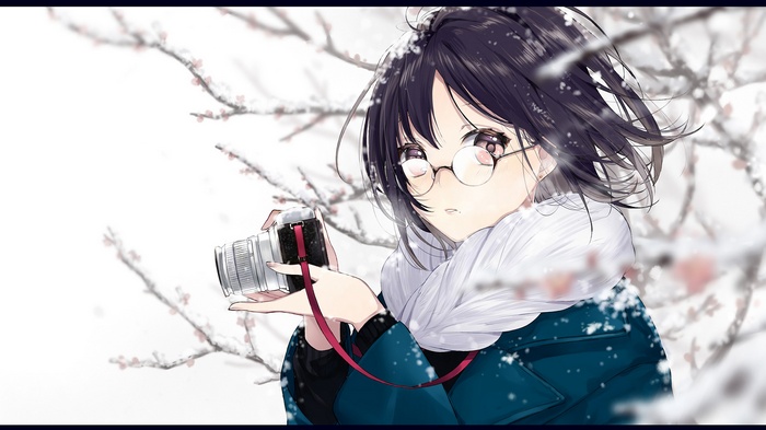 Girl with glasses holding a camera in the snow