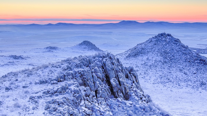 Snowy mountains at sunrise with pastel sky