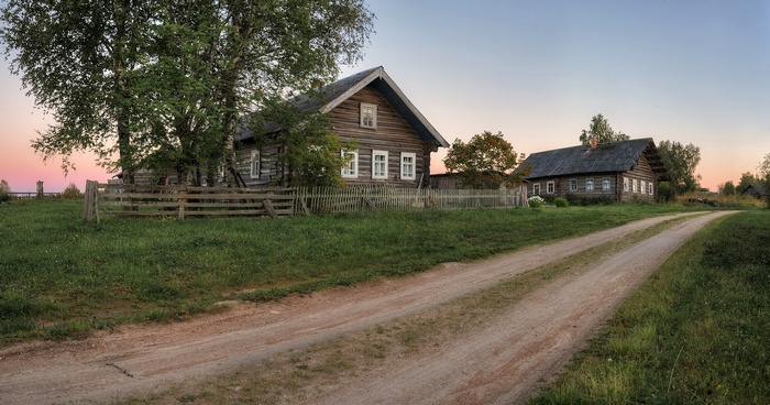 Dirt road leading to wooden houses in a village
