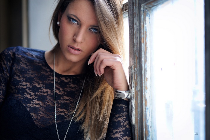 Woman with blue eyes and necklace by window