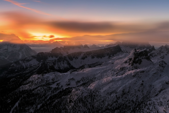 Snowy mountains at sunset with orange sky