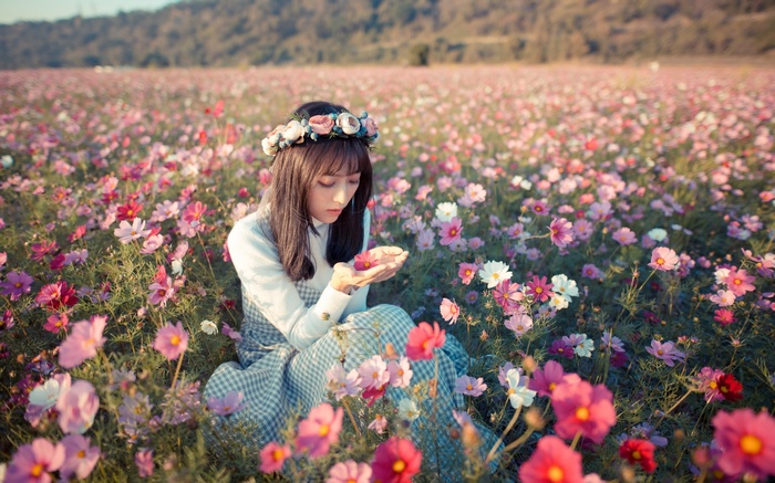 Woman with flower crown in a field of cosmos flowers