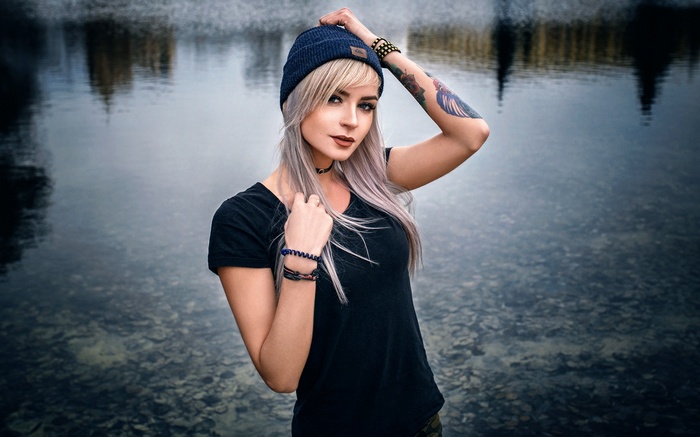 Woman with blonde hair and tattoos wearing a hat