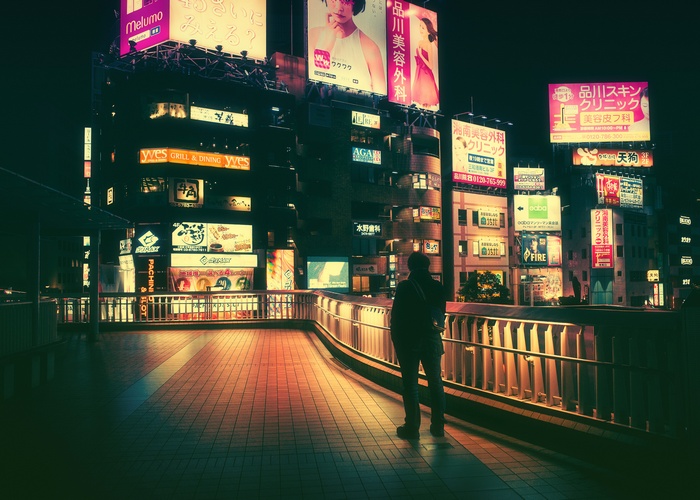 Night view of a city with neon signs and a person