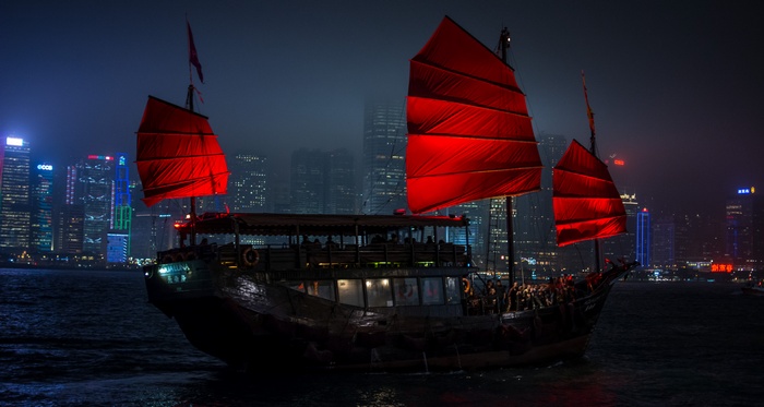 Junk boat with red sails in Hong Kong harbor at night