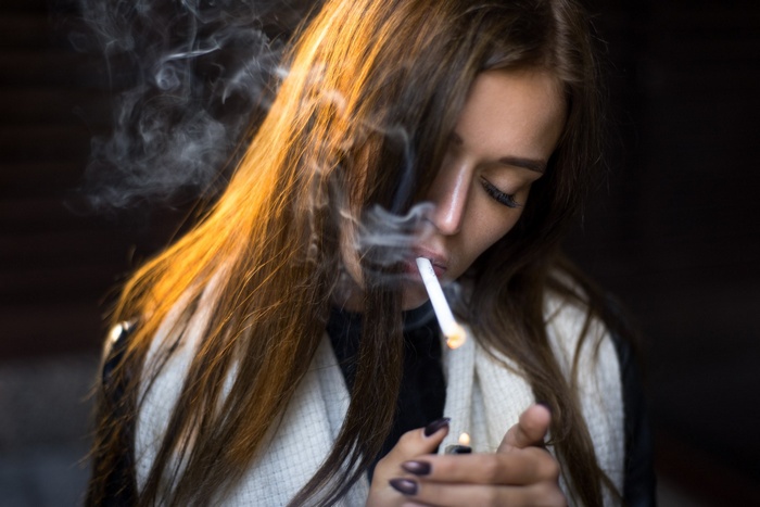 Woman lighting a cigarette with smoke