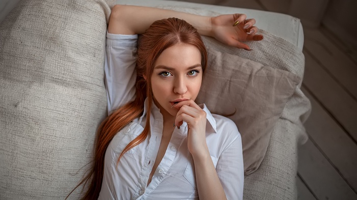 Redhead woman in white shirt lying on couch