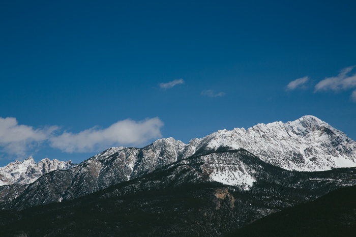 Snowy mountain range under a blue sky with clouds