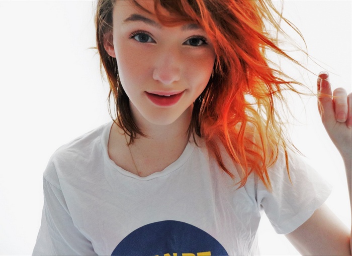 Young woman with orange-dyed hair wearing a t-shirt