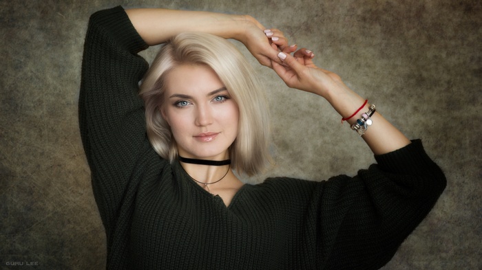 Woman with blonde hair and blue eyes wearing a green sweater