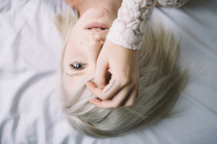 Woman with blonde hair and gray eyes lying down