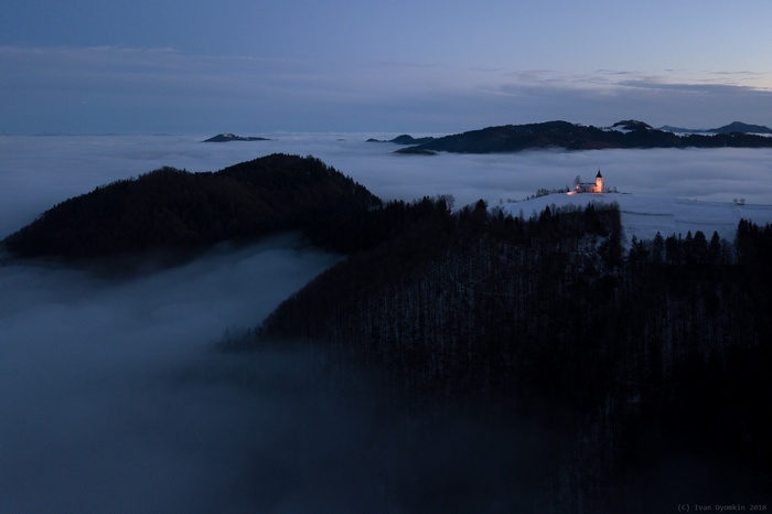 Church on a hill above fog at dusk