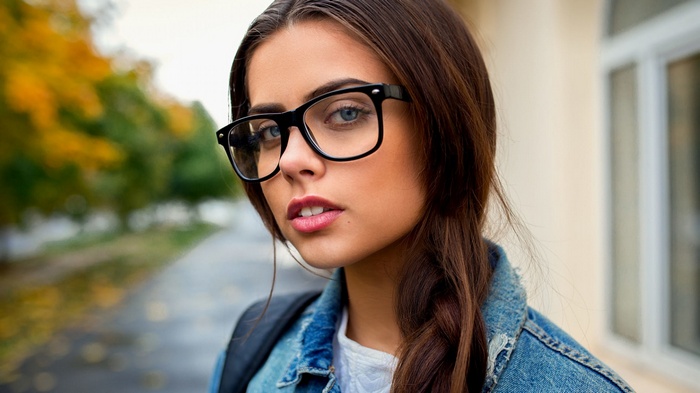 Woman with glasses and braided hair wearing a denim jacket