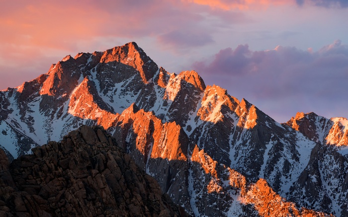 Snowy mountain peaks at sunset with clouds