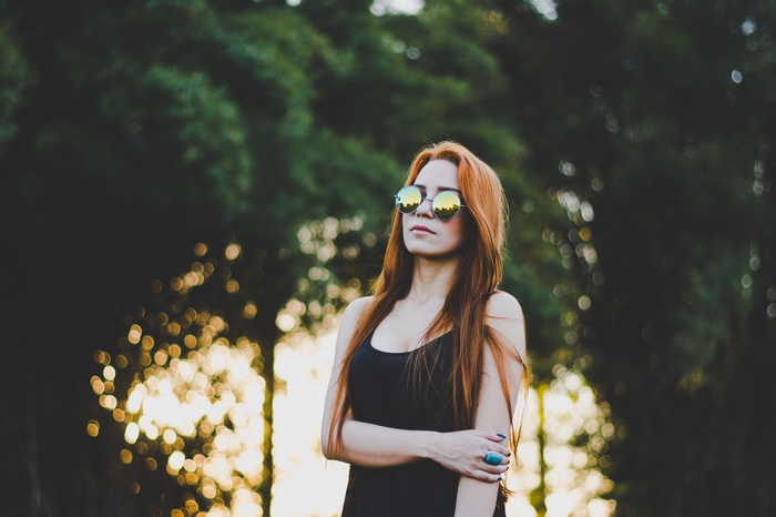 Woman with red hair wearing sunglasses and tank top