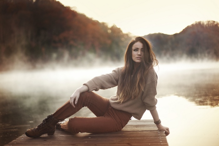 Woman sitting on a wooden dock in mist