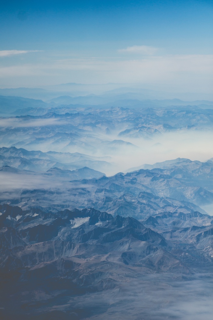 Aerial view of misty mountains and blue sky