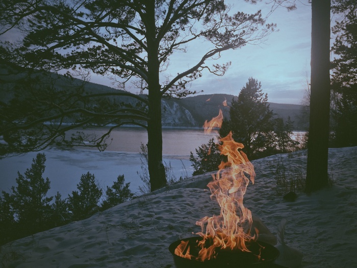 Bonfire by a frozen lake in Russia at sunset