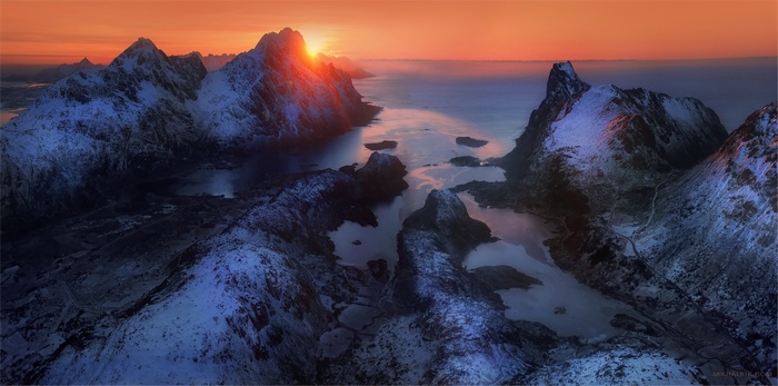 Snowy mountains at sunset over the ocean