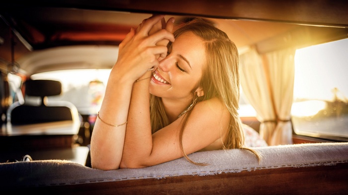 Woman smiling inside a car at sunset
