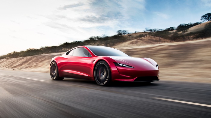 Red Tesla Roadster driving on a road