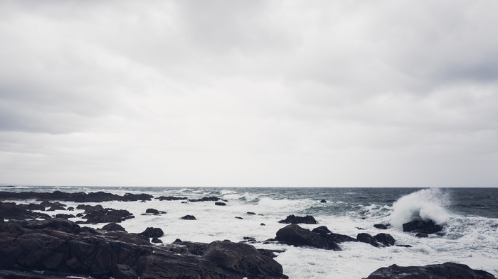 Waves crashing on rocky coast under cloudy sky