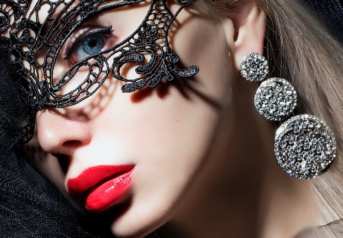 Woman with black lace mask and diamond earrings
