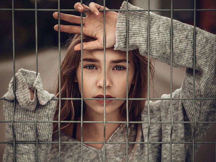 Young woman behind a metal fence