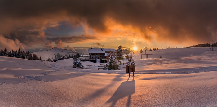 Winter sunset over a snowy mountain landscape with a lodge
