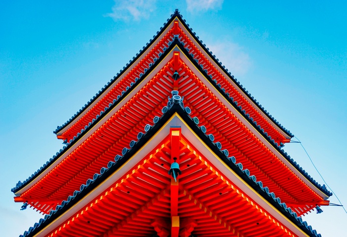 Close-up of a red Japanese pagoda against a blue sky
