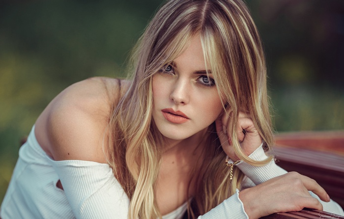 Woman with blonde hair and blue eyes wearing a white sweater