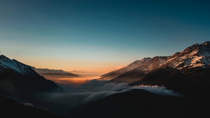 Sunrise over misty mountains with snow-capped peaks
