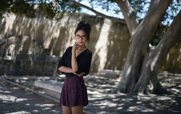 Woman with glasses in a black top and skirt outdoors
