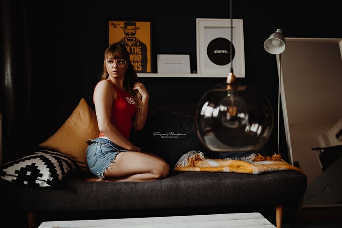Woman in red tank top and jean shorts sitting on a couch