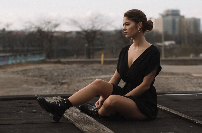 Woman in black dress sitting on rooftop