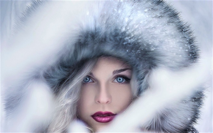 Woman in fur hood with blue eyes and purple lipstick in snow