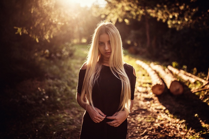 Woman with long blonde hair in a black dress outdoors