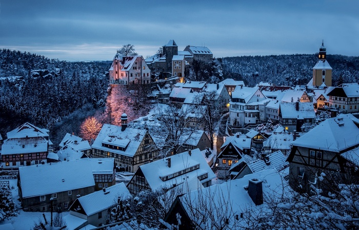 Snowy Hohnstein town with castle and forest at dusk