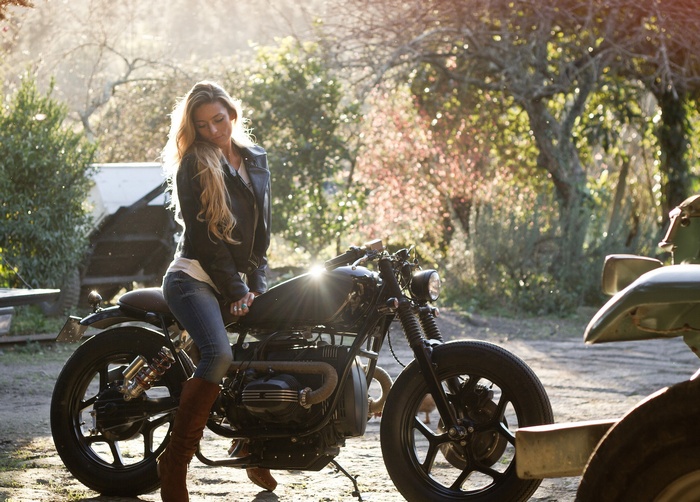 Blonde woman in leather jacket sitting on a motorcycle
