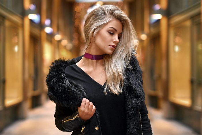 Woman with blonde hair wearing a black coat and choker