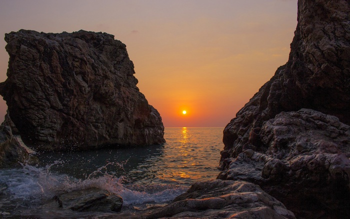 Sunset over the ocean between rocks