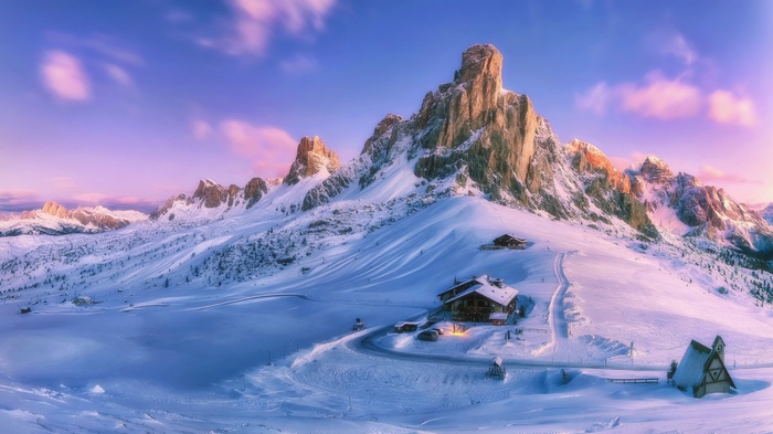 Snowy mountains with lodges at sunset