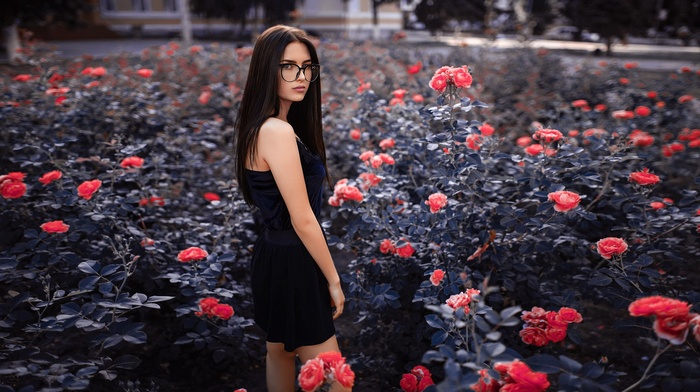 Woman in black dress with glasses in a rose garden