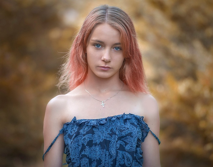 Young woman with pink hair and blue eyes wearing a blue dress