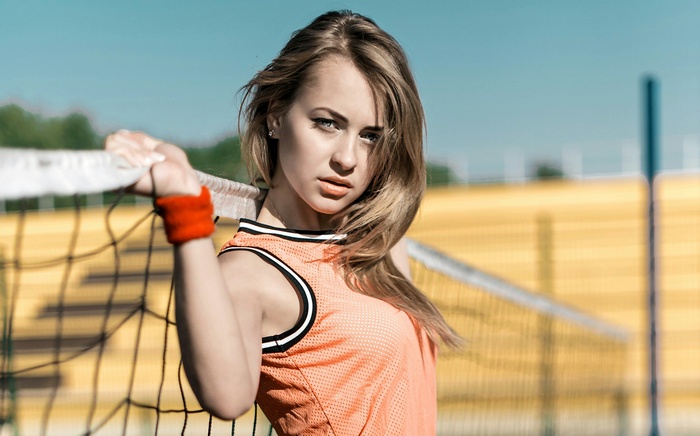 Woman in orange top holding volleyball net